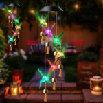 Two hummingbird Solar Wind Chimes hanging outside in a garden in the evening