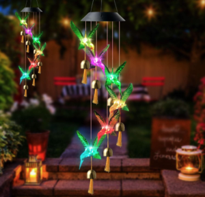 Two hummingbird Solar Wind Chimes hanging outside in a garden in the evening