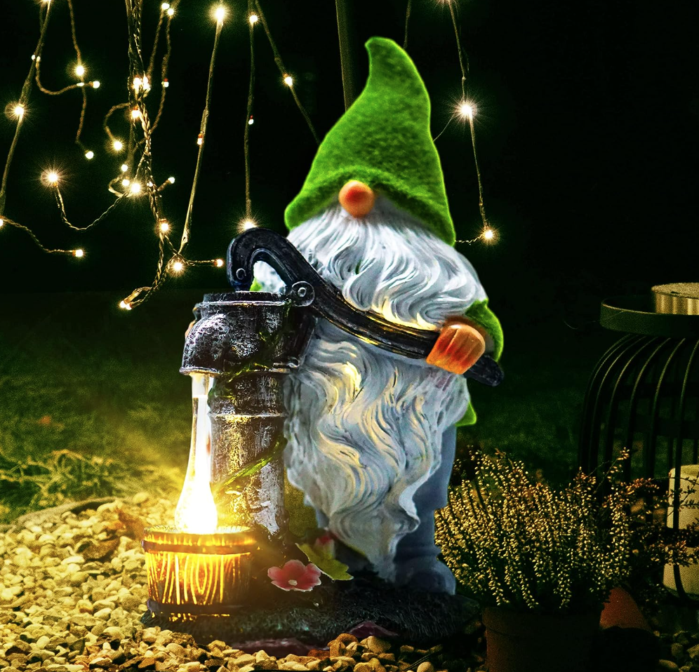 Funny gnome with waterpump outside in a garden in the evening